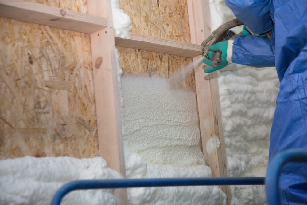Technicien en isolation qui pulvérise du polyuréthane à alvéoles ouvertes dans les murs intérieurs d'une nouvelle maison à Shawinigan près de Trois-Rivières